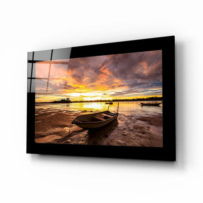 Serene sunset over water glass wall art with boat on shore
