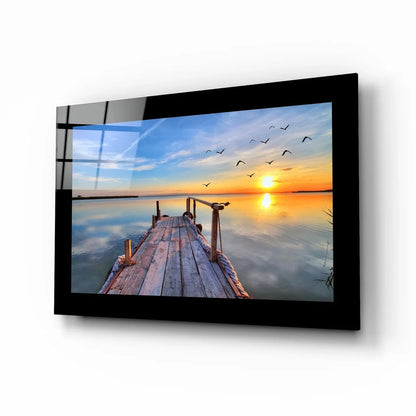 Glass wall art of dock at sunset with birds and misty mountain reflections