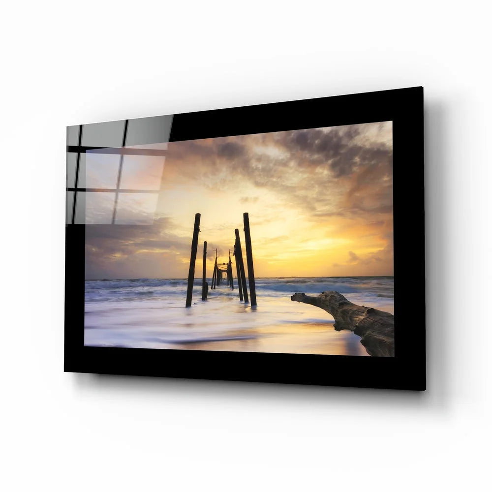 Stunning sunset over ocean pilings in black-framed glass wall art