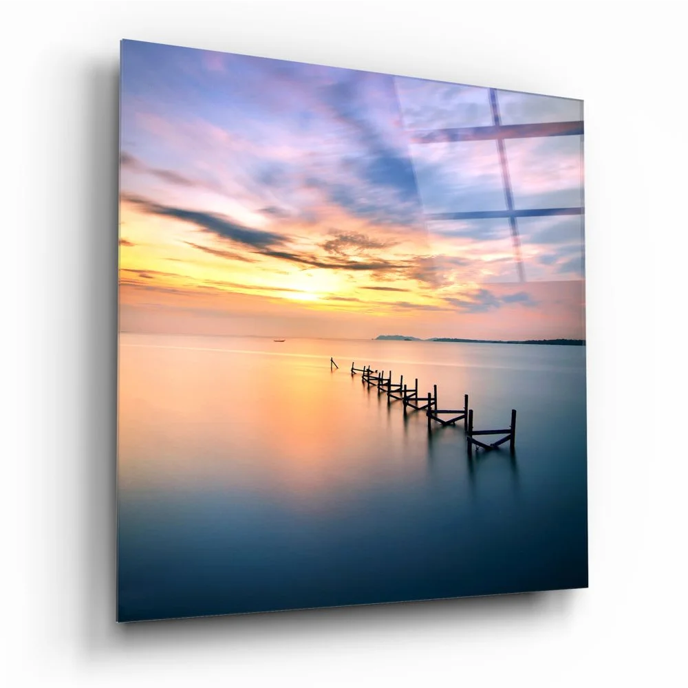 Serene sunset over calm water with silhouetted pilings on tempered glass art
