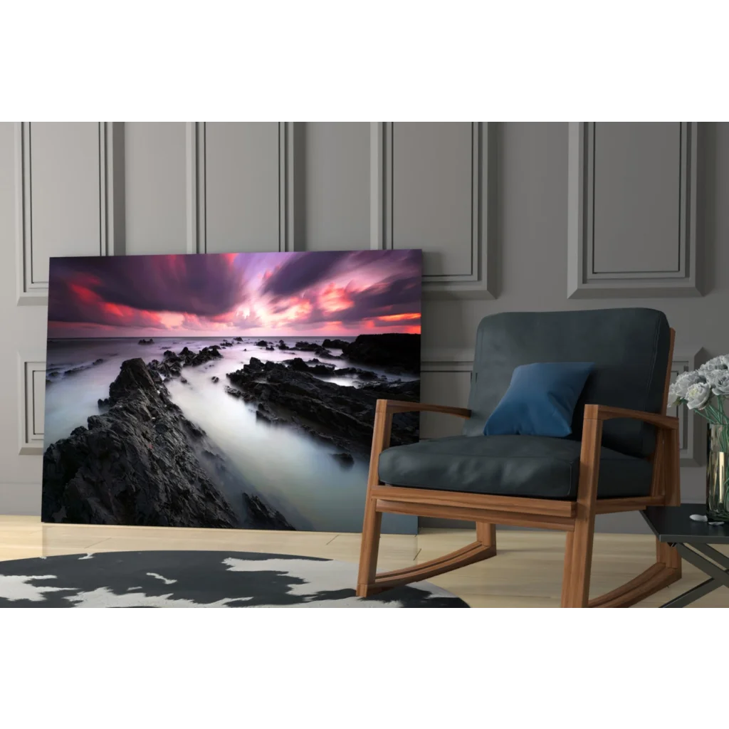 Vibrant coastal sunset glass wall art print with swirling purples, pinks, and oranges above rocks and water