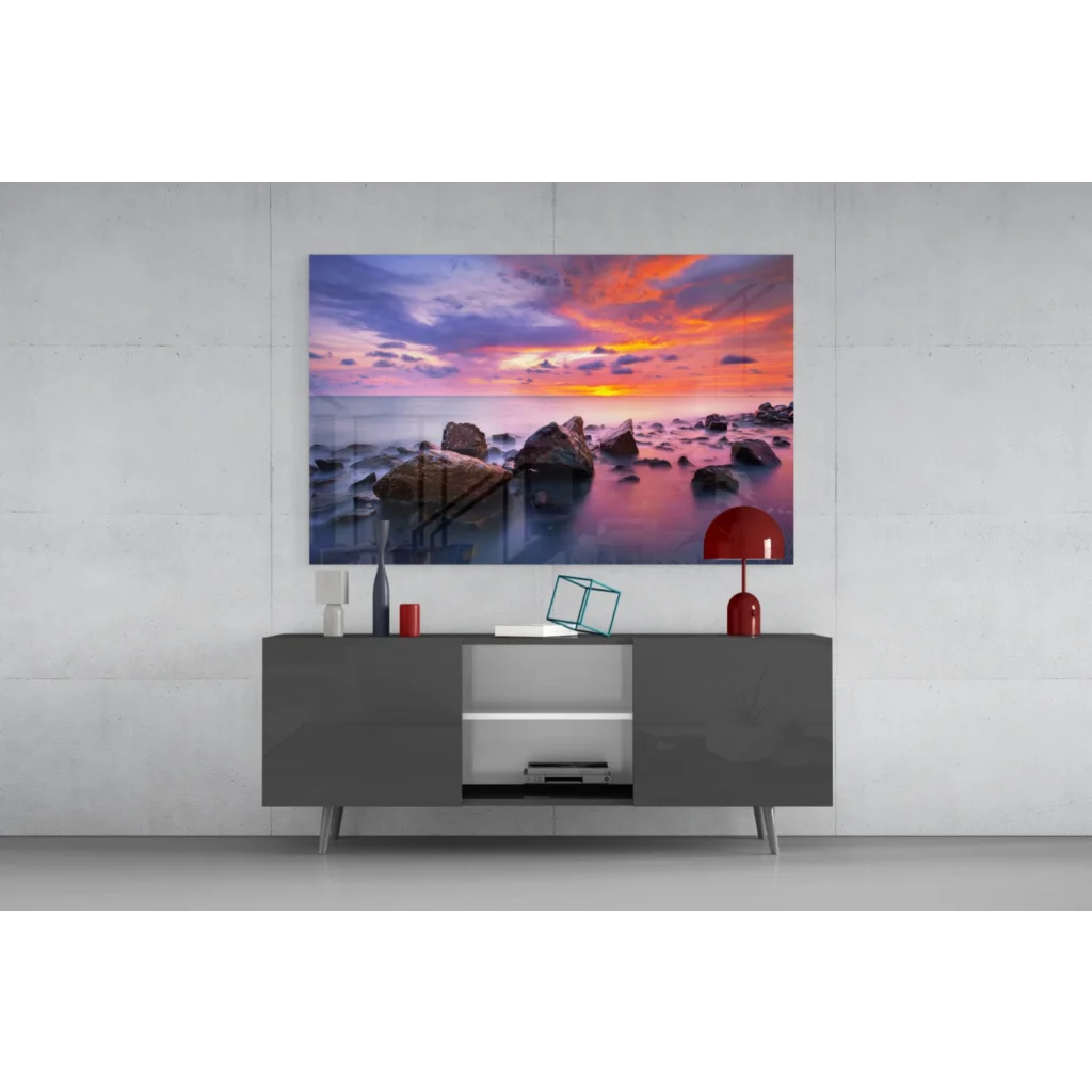 Vibrant sunset seascape glass wall art with orange, pink, purple hues on calm water over rocks