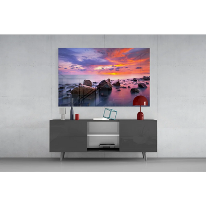 Vibrant sunset seascape glass wall art with orange, pink, purple hues on calm water over rocks