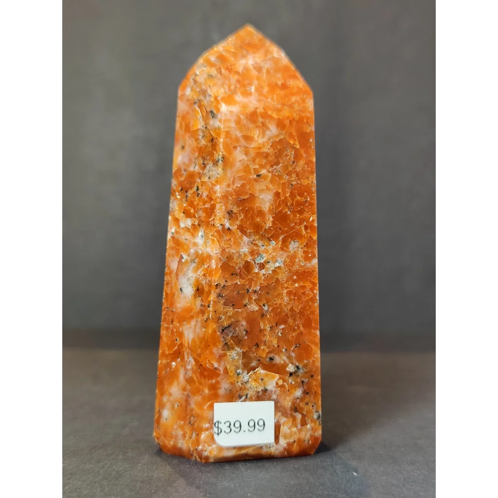 Tall orange sunstone polished obelisk tower sculpture with pointed top and speckled surface in polished obelisk tower form
