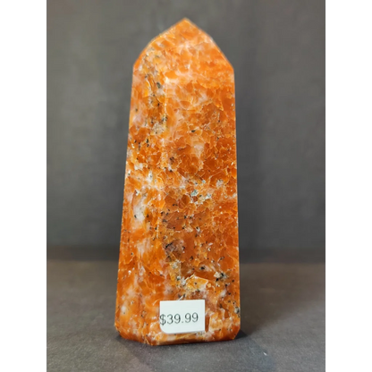 Tall orange sunstone polished obelisk tower sculpture with pointed top and speckled surface in polished obelisk tower form