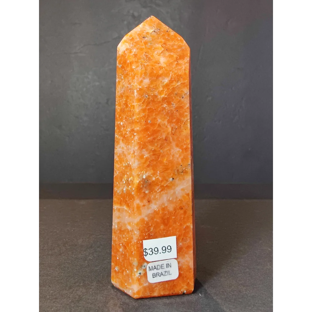 Sunstone polished obelisk tower sculpture featuring a tall polished orange stone obelisk with speckled texture and pointed top