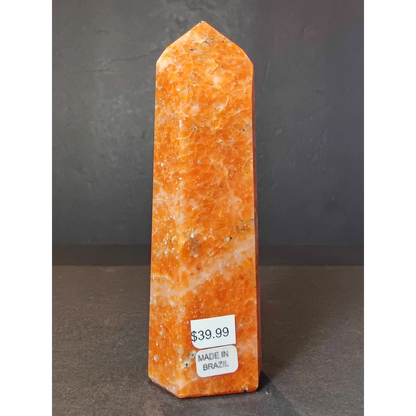 Sunstone polished obelisk tower sculpture featuring a tall polished orange stone obelisk with speckled texture and pointed top