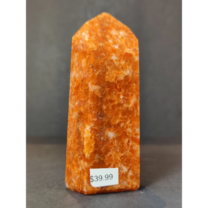 Sunstone polished obelisk tower sculpture featuring a tall orange-yellow crystal with honeycomb texture and white veining