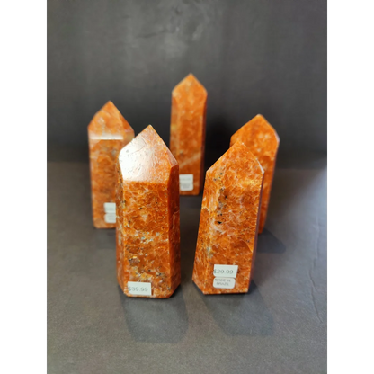 Sunstone polished obelisk featuring orange-orange calcite crystal pillars with a speckled translucent appearance