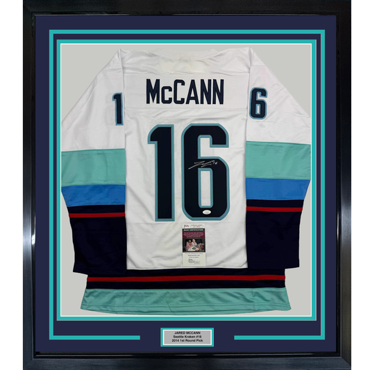 Framed white Seattle Kraken hockey jersey #16 with "McCann" nameplate, signed, displaying turquoise and navy striping with JSA authentication certificate.