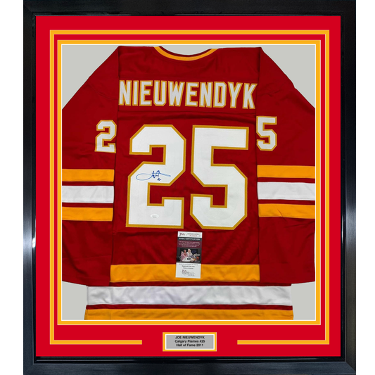 Framed red Calgary Flames hockey jersey number 25 with Nieuwendyk nameplate and signature, displayed front-facing with yellow and red border matting.