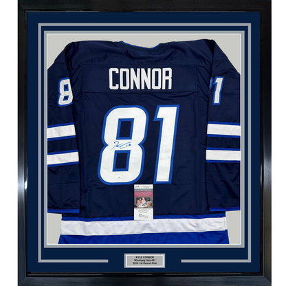 Framed navy Winnipeg Jets hockey jersey number 81 with "CONNOR" nameplate and signed autograph, displayed flat against white matting with authentication certificate visible.