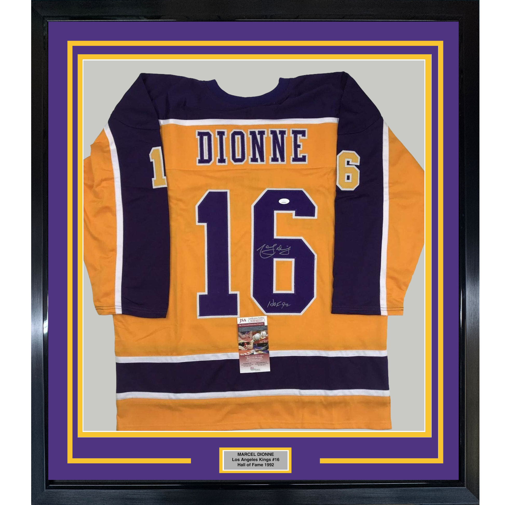 Framed orange and navy Los Angeles Kings hockey jersey #16 with "DIONNE" nameplate, signed, displayed flat against purple and gold matting with authentication certificate.