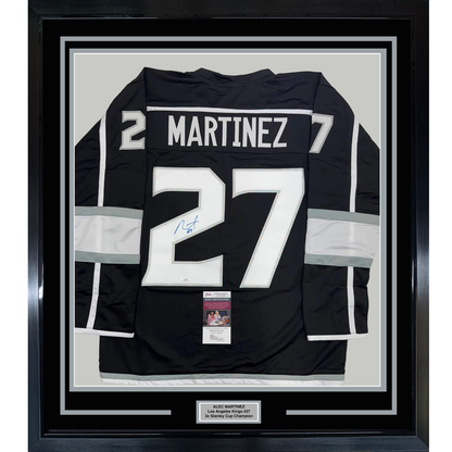 Black Los Angeles Kings hockey jersey number 27 with "MARTINEZ" nameplate, signed in blue ink, displayed in black frame with white matting and JSA authentication certificate.