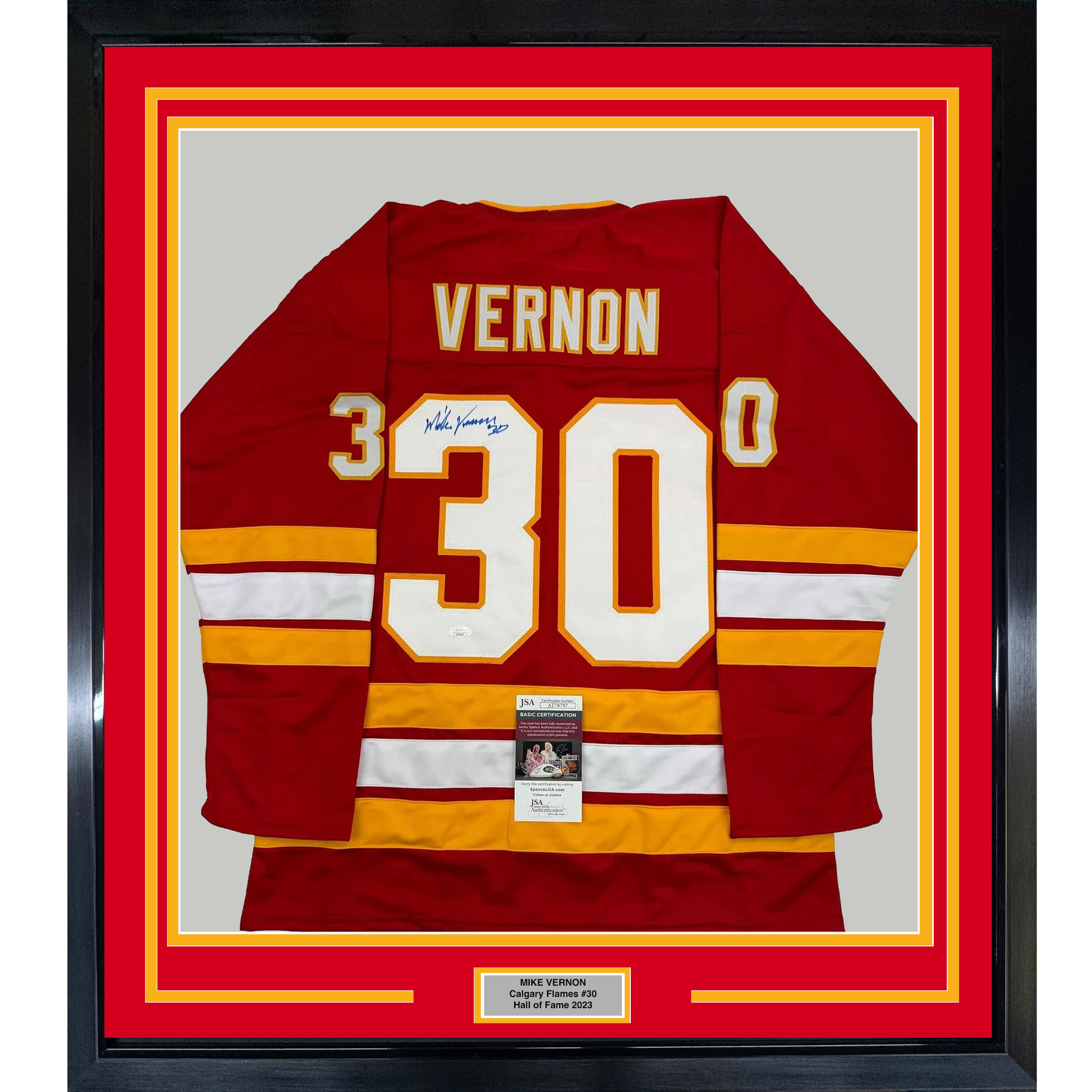 Framed red Calgary Flames hockey jersey #30 with "VERNON" nameplate, signed, displayed flat against gray backing with red and yellow matting.