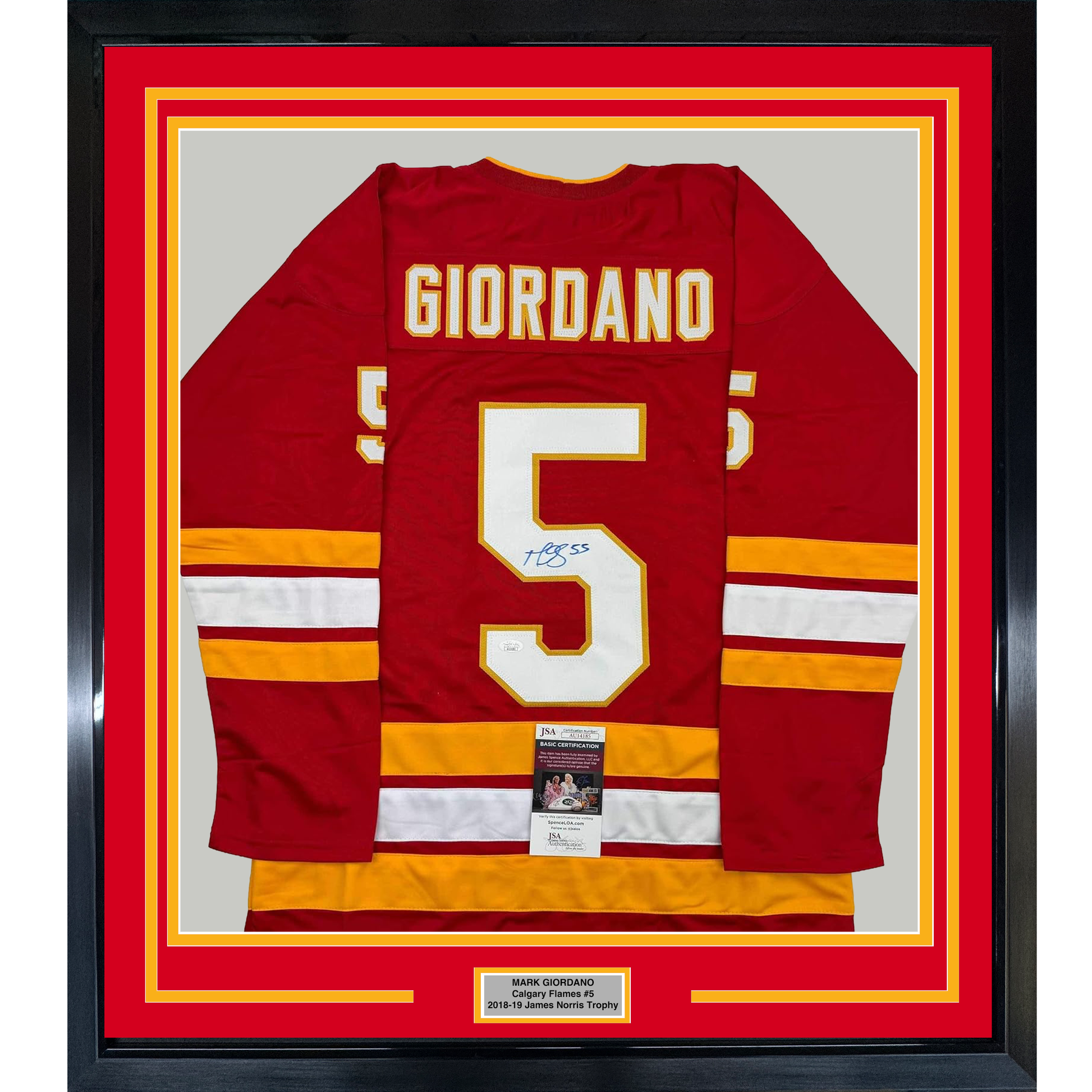 Framed red Calgary Flames hockey jersey number 5 with "GIORDANO" nameplate, signed in blue ink, displayed flat against gray background with yellow and red matting.