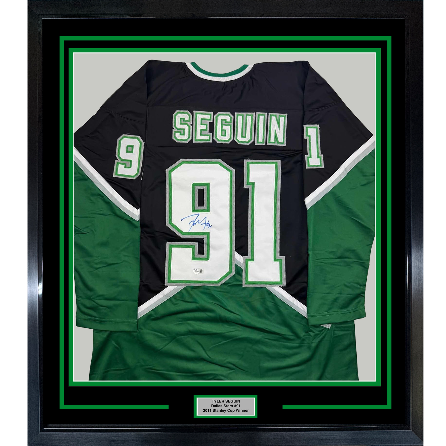 Framed black and green Dallas Stars hockey jersey #91 signed by Tyler Seguin, displayed flat with nameplate below.