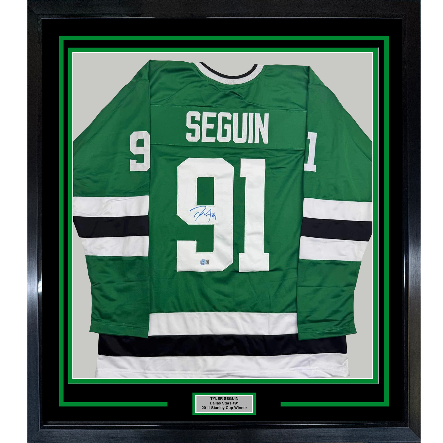Green Dallas Stars hockey jersey #91 signed by Tyler Seguin, framed with white and black stripes, displayed flat against light background.