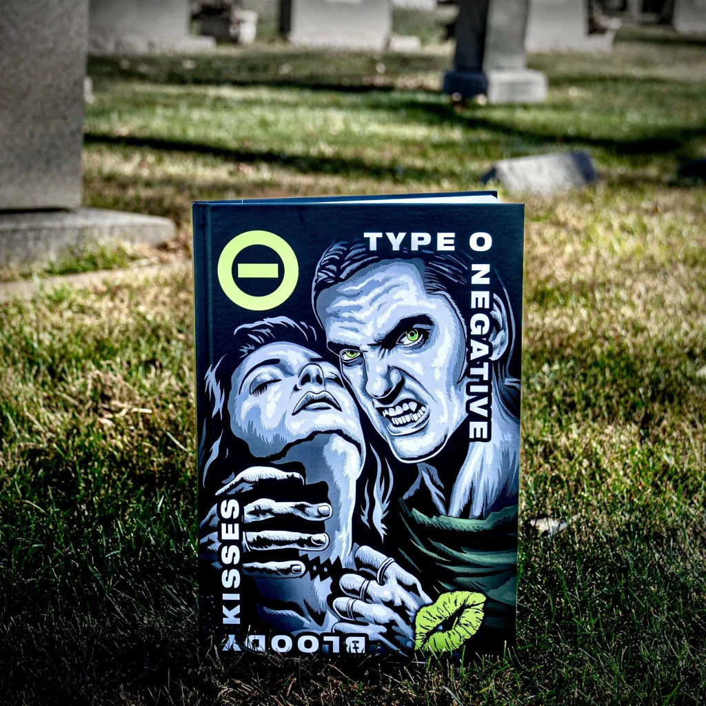 Dark blue hardcover book type o negative bloody kisses featuring stylized man with green eyes and woman neon yellow accents