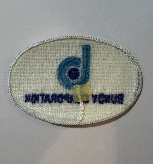 Reverse of the Bundy Corporation patch showing open weave backing and factory bundling tab