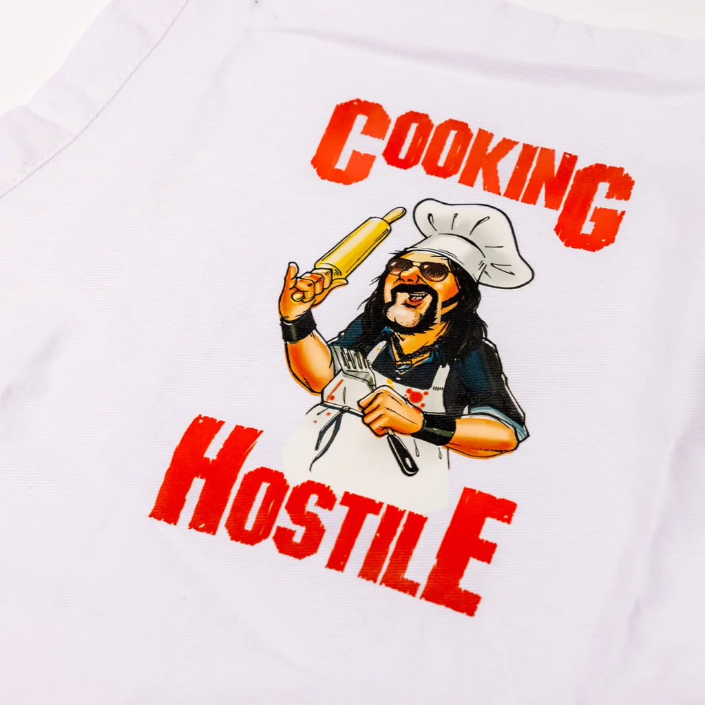 White apron with Cooking Hostile cartoon design from Vinnie Paul Texas Beef Grilling Cookbook