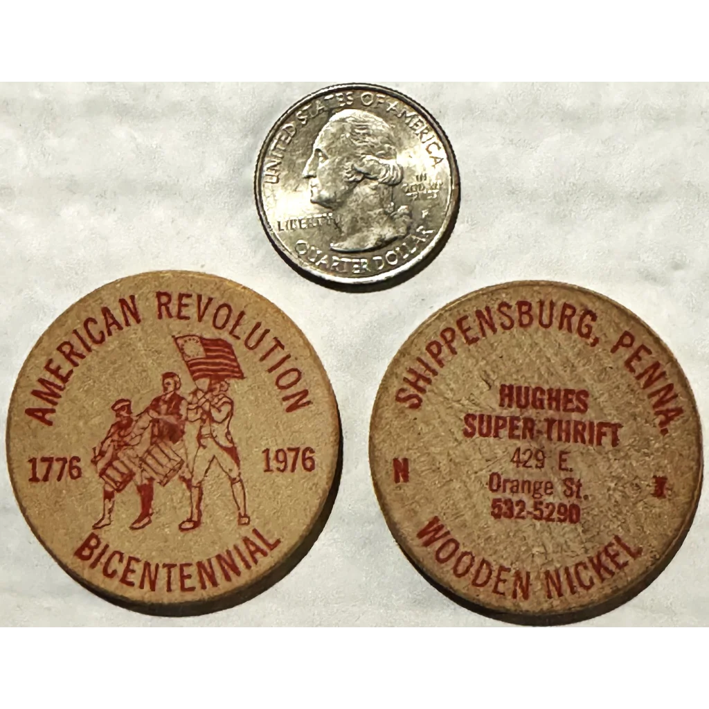 Two wooden tokens and a silver quarter celebrating the American Revolution