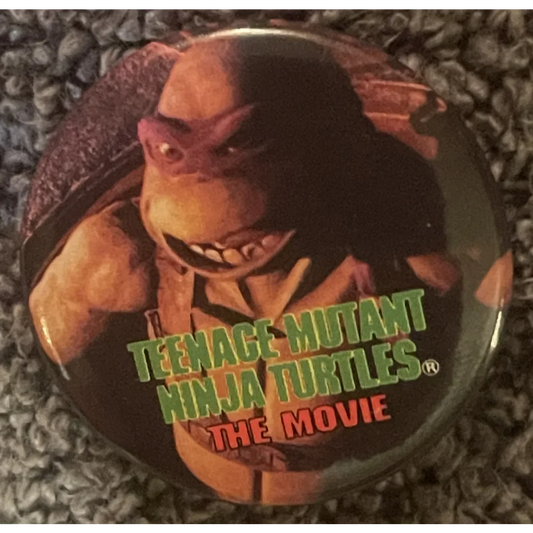 Circular pin showing a Teenage Mutant Ninja Turtle and movie title for collectors