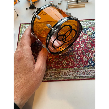 Orange drum head with black rim logo on vintage drum rug for scale drum kit
