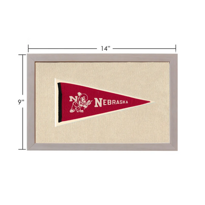 Vintage Nebraska pennant with red design, white lettering, and cartoon mascot in gray frame