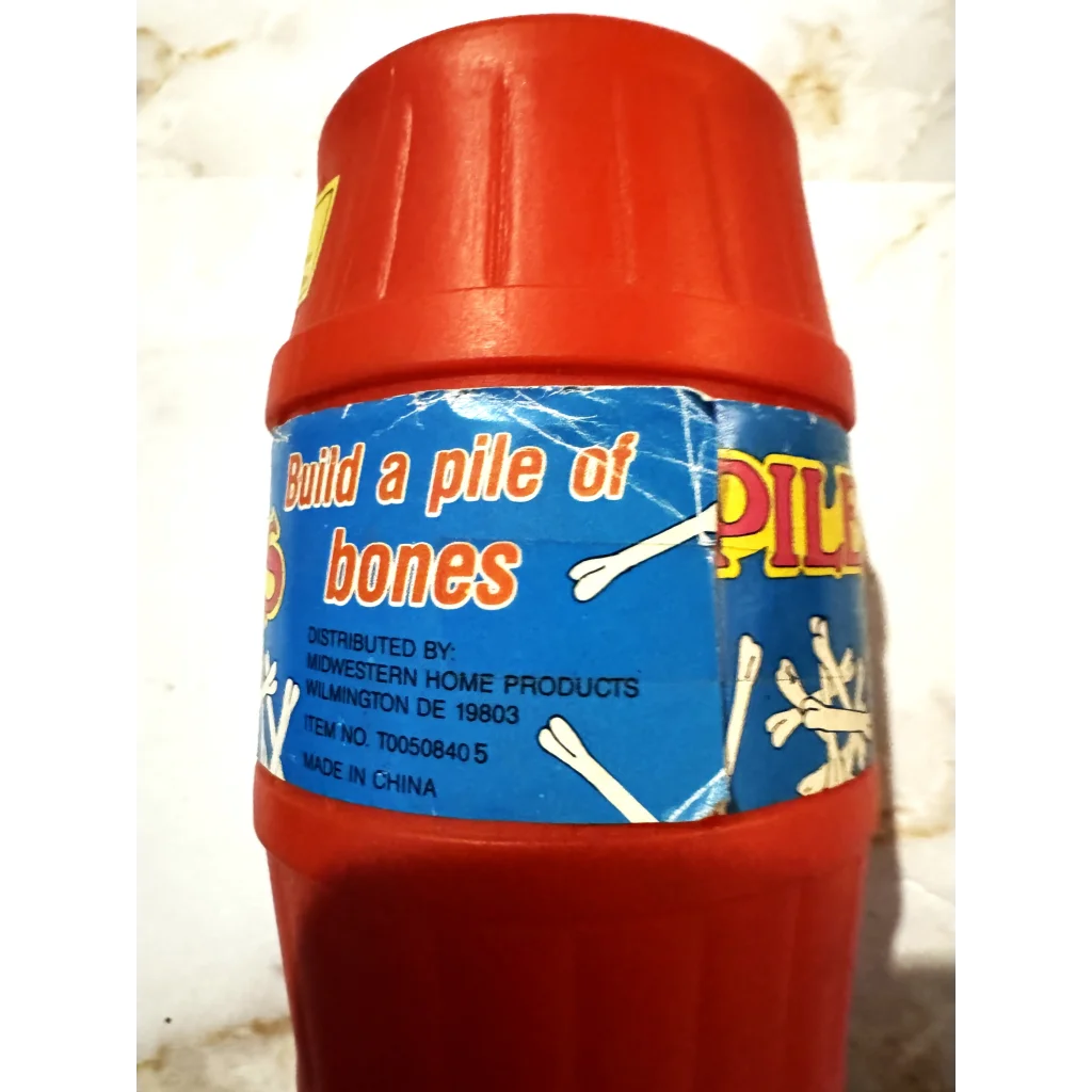 Red plastic container with blue label for Vintage Pile The Bones Game toy