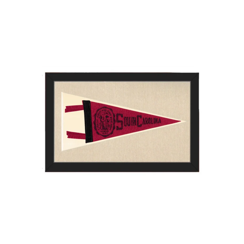 A framed vintage south carolina pennant with a maroon triangular flag and black lettering on textured backing