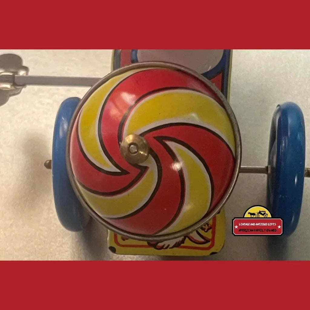 Colorful vintage tin pull-along toy with swirled design and blue wheels from the 70s 80s