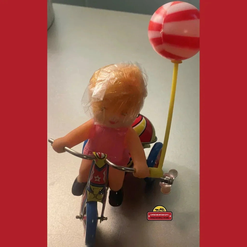 Toy figure on a vintage tin tricycle with balloon, perfect for nostalgic collectors