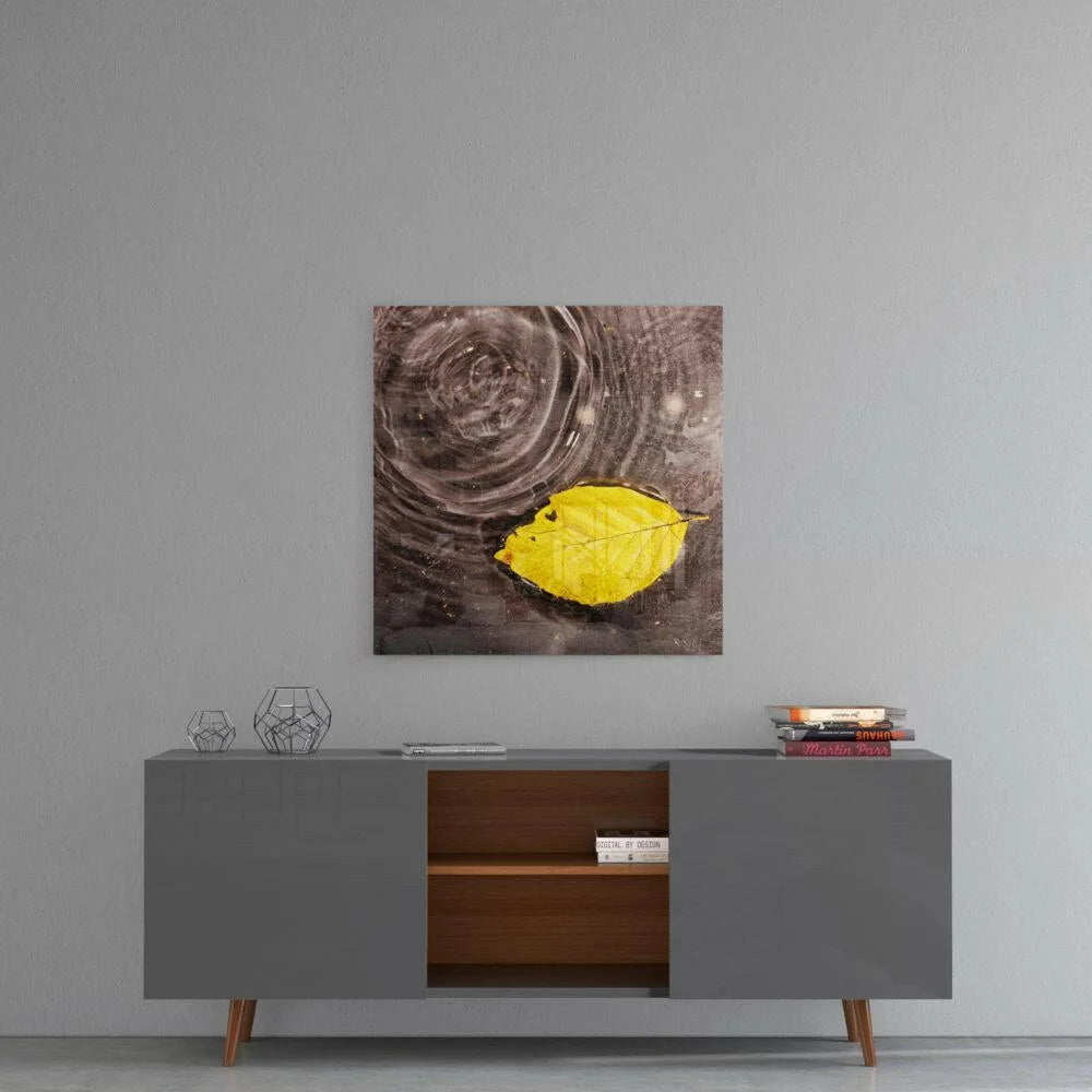 Vibrant yellow leaf on rippling water in stunning glass wall art