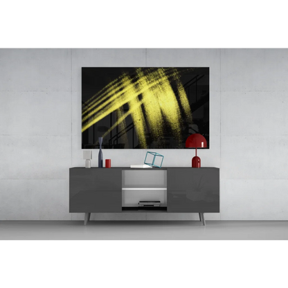Bold yellow brushstroke glass wall art on black canvas above gray console