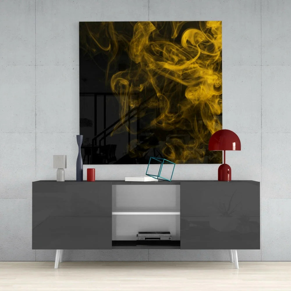 Vibrant yellow smoke abstract glass wall art panel on black background above gray console