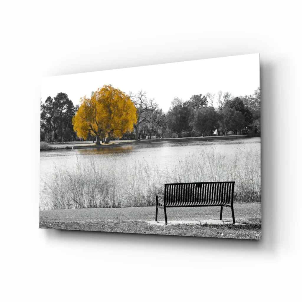 Black metal bench by lake under golden tree in glass wall art print