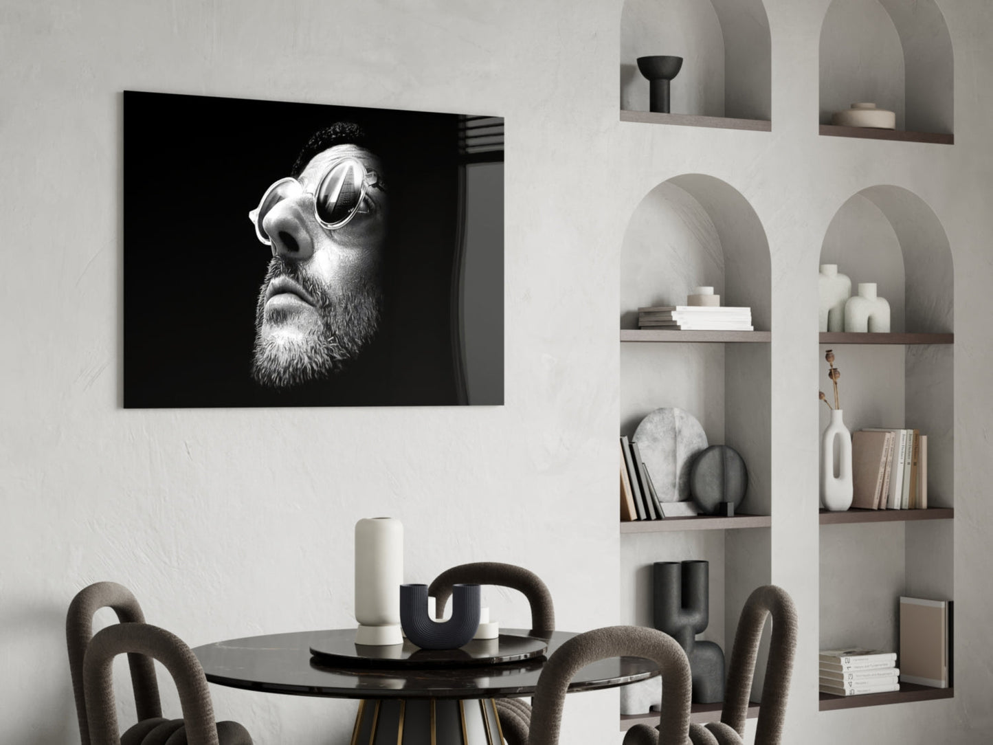 Black and white portrait of bearded man wearing oval sunglasses displayed on wall above dining table.