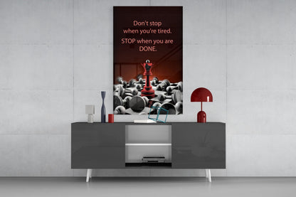 Motivational glass wall art with red chess piece and gray spheres displayed above gray console table with red lamp and decorative accessories.