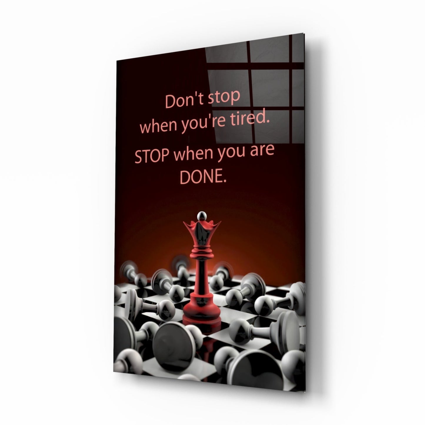 Angled view of glass wall art displaying a red chess queen surrounded by white pawns with motivational text on dark background.