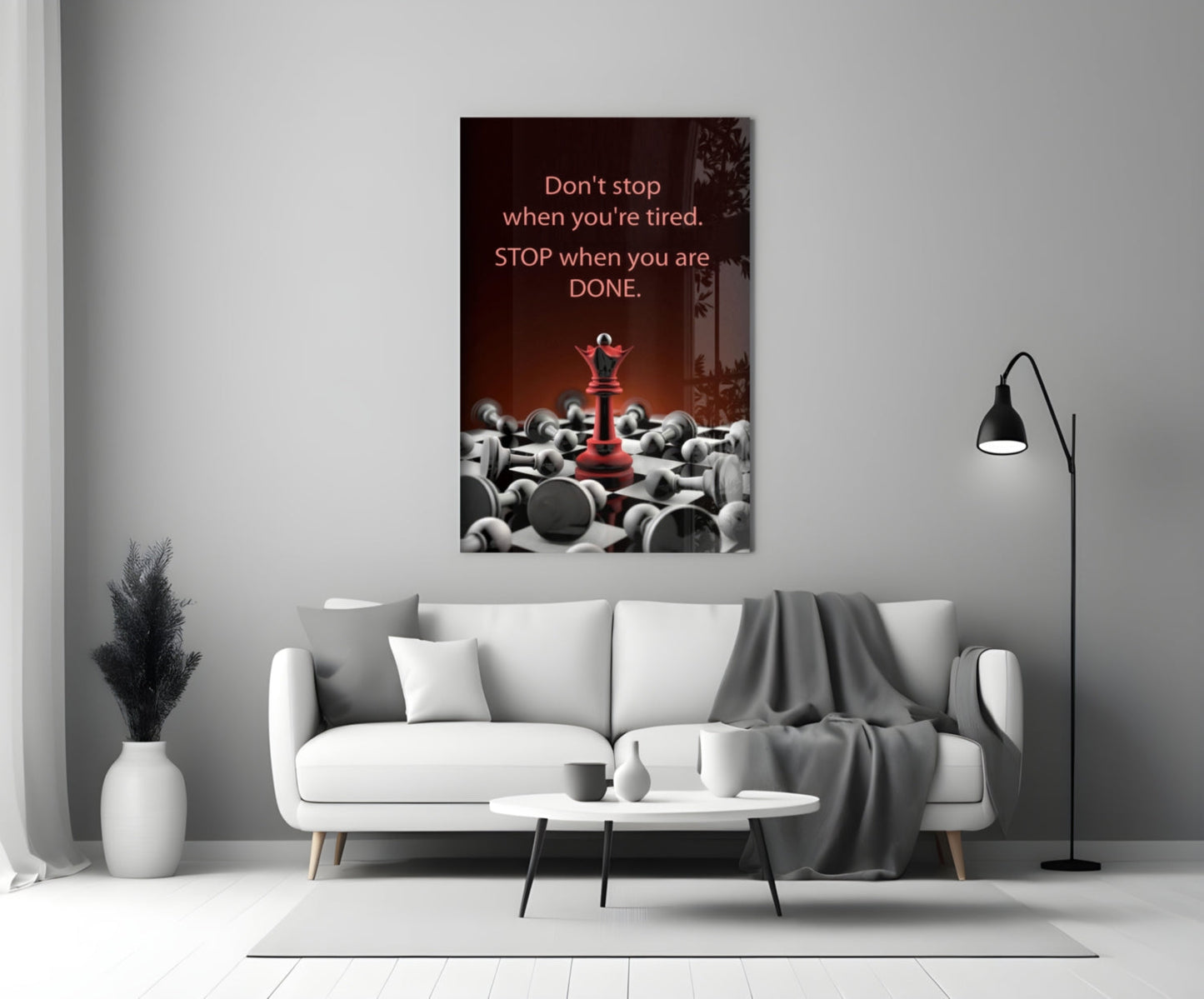 Motivational glass wall art with red chess piece and scattered gray pieces, mounted above white sofa in minimalist living room.