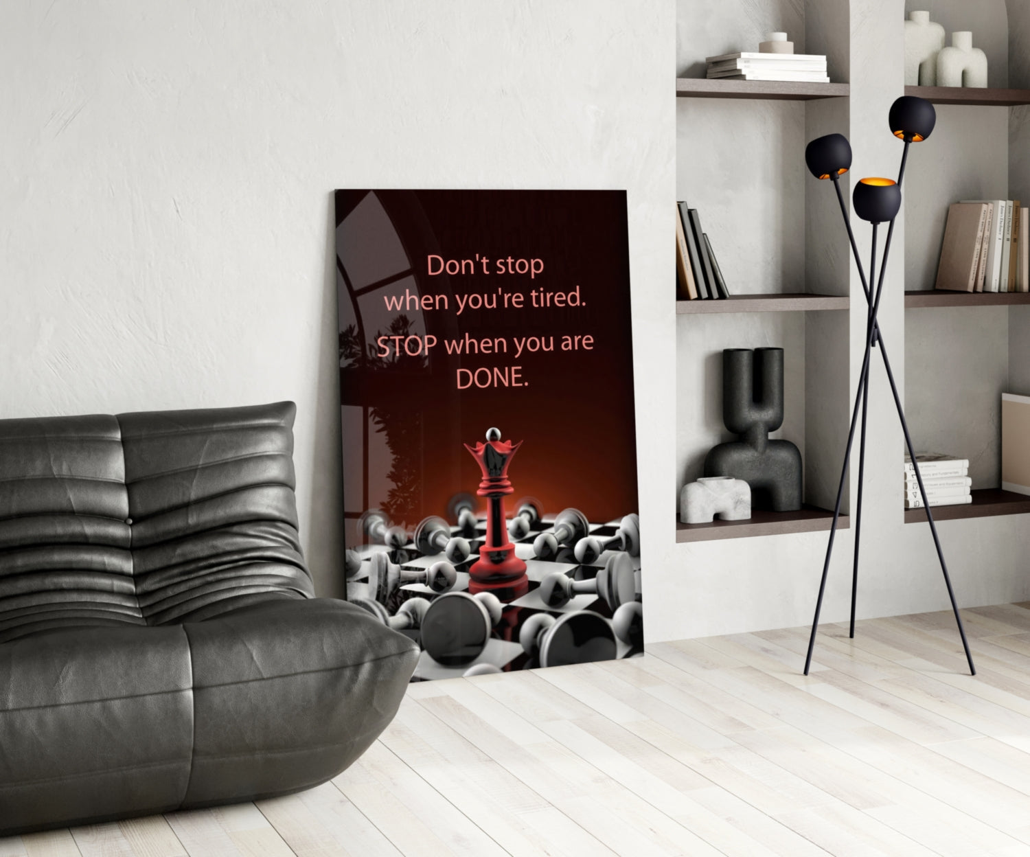 Motivational glass wall art displayed in modern living room with gray sofa, showing chess pieces and red queen with inspirational text.