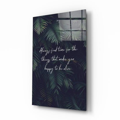 Angled view of glass wall art with dark foliage background and white script text about finding time for happiness.