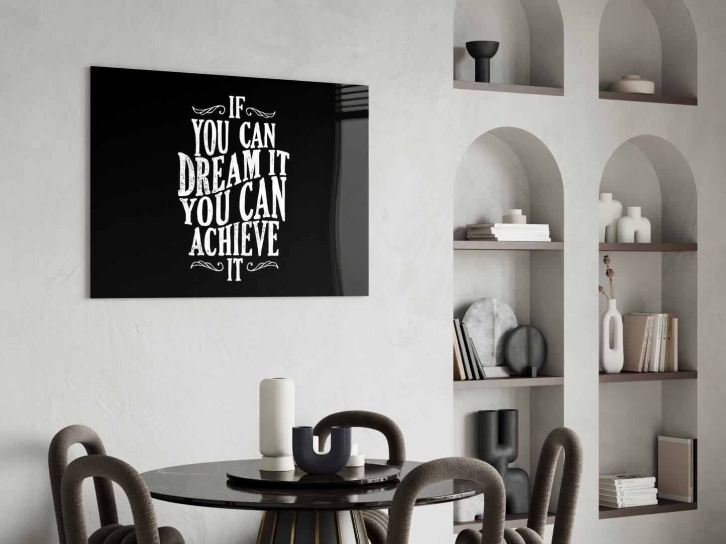 Black glass wall art with white motivational text displayed above a round black dining table with upholstered chairs and built-in shelving.