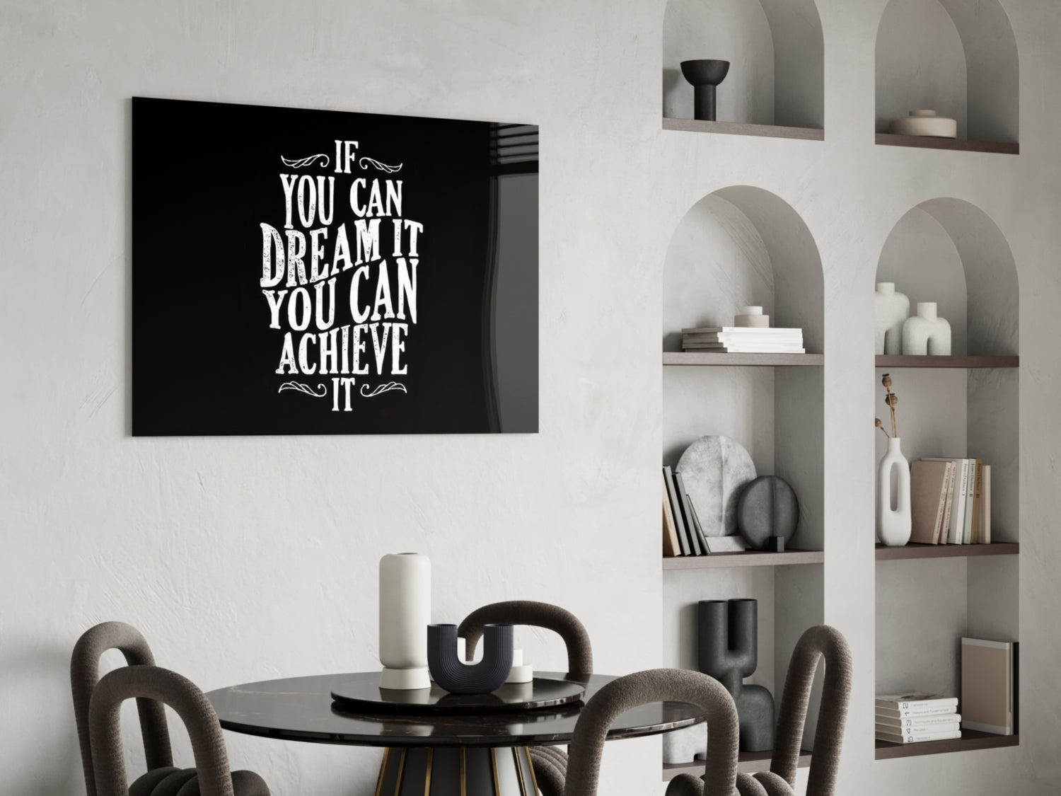 Black glass wall art with white motivational text displayed above a round black dining table with upholstered chairs and built-in shelving.