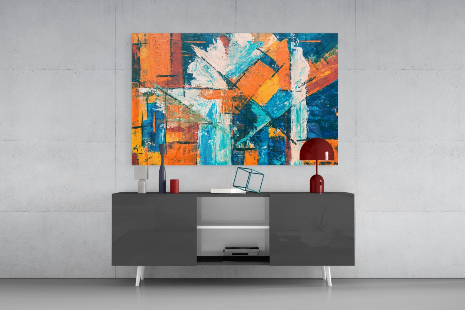 Vibrant abstract glass wall art in orange, blue, and yellow hanging above a modern dark console table with accessories.