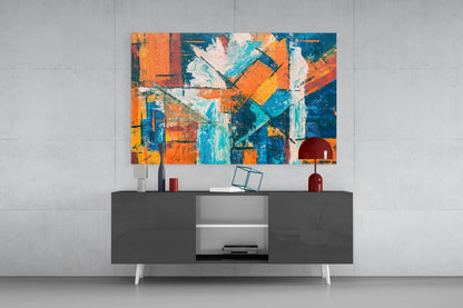 Vibrant abstract glass wall art in orange, blue, and yellow hanging above a modern dark console table with accessories.