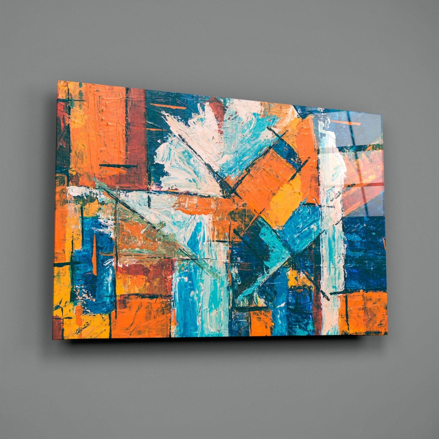 Abstract glass wall art featuring vibrant orange, blue, and turquoise geometric shapes with white accents, displayed at an angle against gray background.
