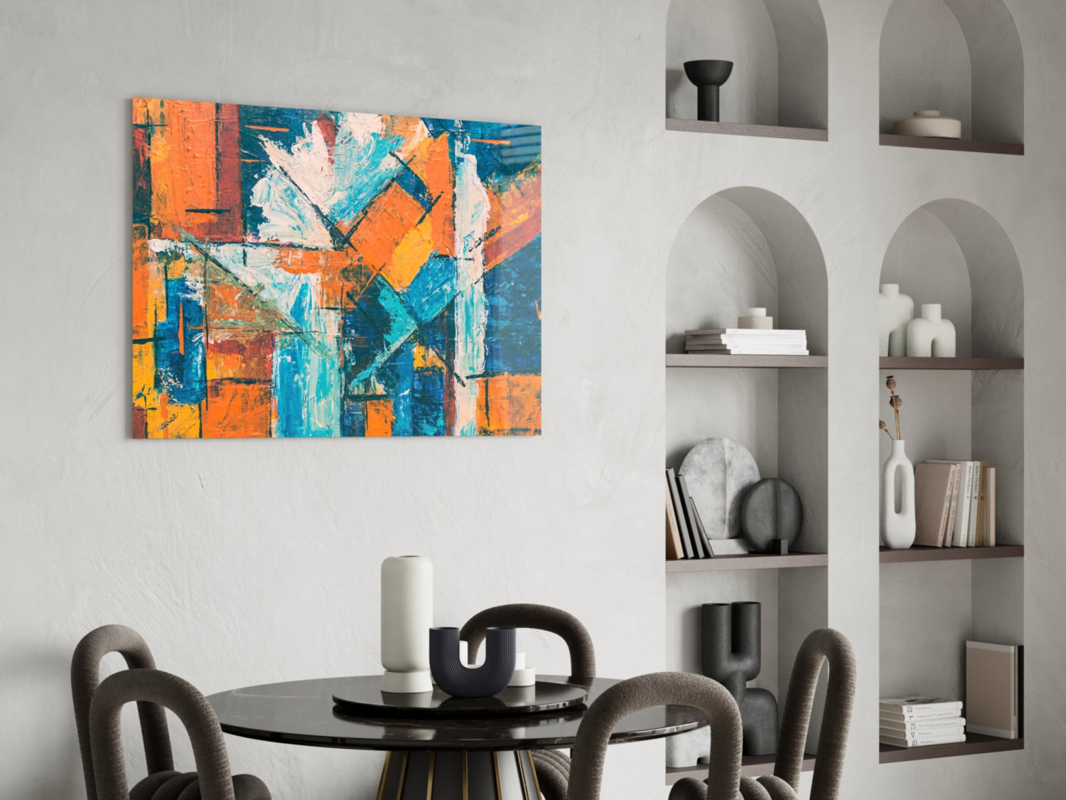 Abstract glass wall art with orange, blue, and teal geometric patterns displayed above a dining table in a modern interior.