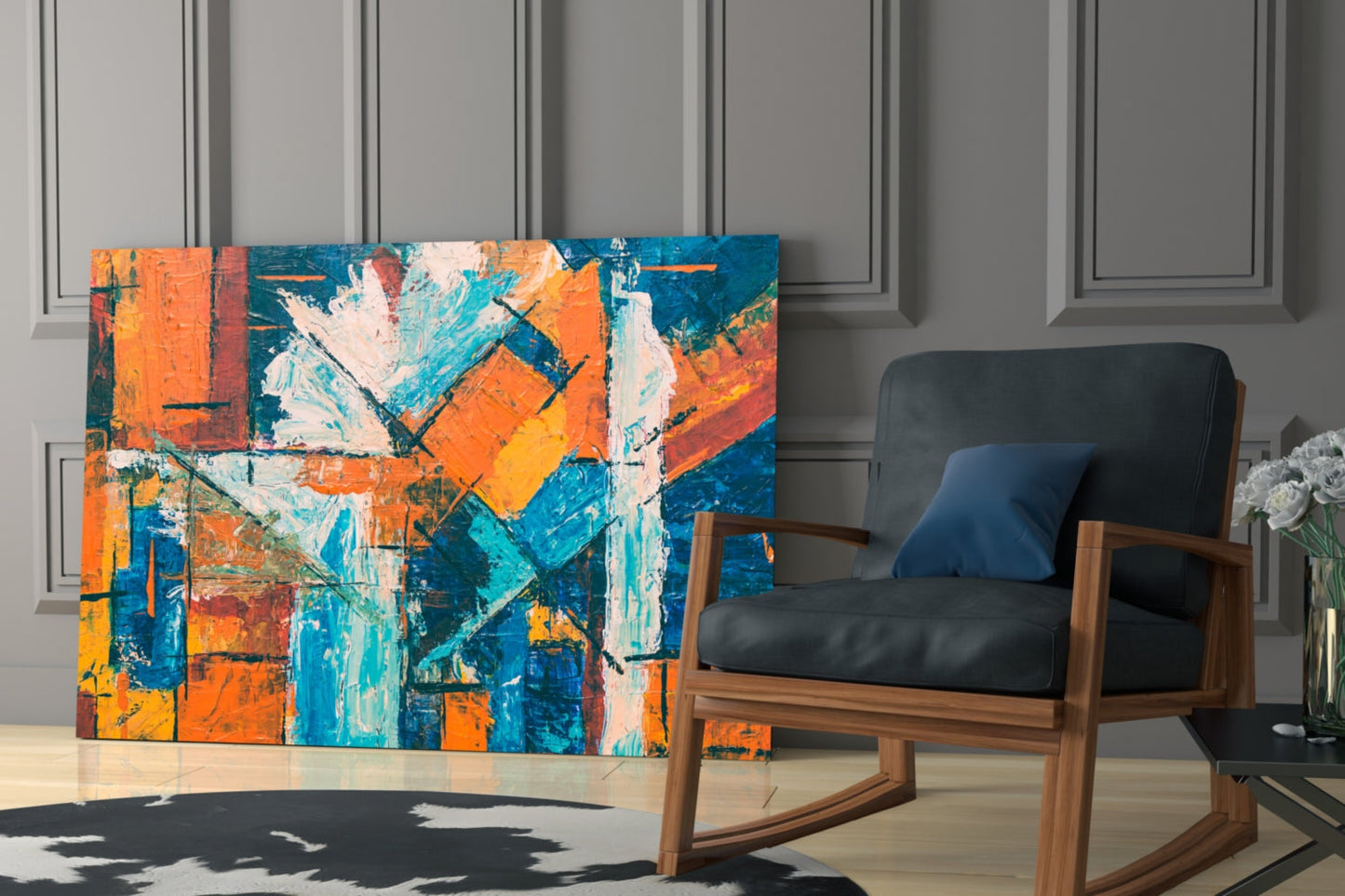Colorful abstract glass wall art in blue, orange, and teal displayed behind a wooden rocking chair in a modern interior.
